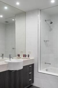 a white bathroom with a sink and a shower at Tyrian Serviced Apartments Fitzroy in Melbourne