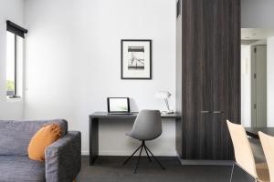 a living room with a couch and a desk at Tyrian Serviced Apartments Fitzroy in Melbourne