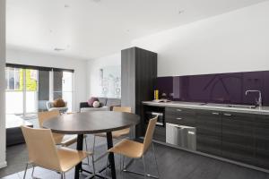 a kitchen with a table and chairs in a room at Tyrian Serviced Apartments Fitzroy in Melbourne