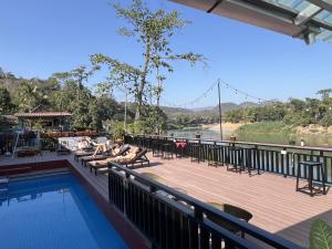 una terraza con sillas y una piscina junto a un río en Funny Riverside Backpackers, en Luang Prabang