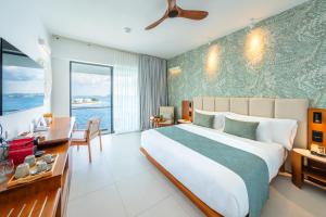 ein großes Schlafzimmer mit einem großen Bett und einem Schreibtisch in der Unterkunft Barceló Nasandhura Male in Male City