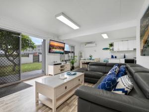 ein Wohnzimmer mit einem Sofa und einem TV in der Unterkunft Skyes Beach House - The entertainer - Pet Friendly in Malua Bay