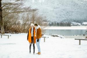 due persone in piedi nella neve vicino a un lago di Seehotel Berau a St. Wolfgang