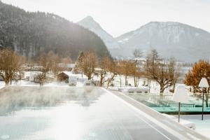 una vasca idromassaggio con montagne innevate sullo sfondo di Seehotel Berau a St. Wolfgang