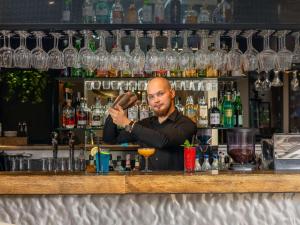 un homme se tenant derrière un bar pour boire un verre dans l'établissement Novotel Gdańsk Marina, à Gdańsk