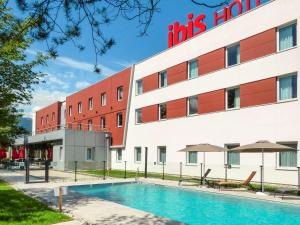 un hôtel avec une piscine en face d'un bâtiment dans l'établissement Ibis Saint-Genis-Pouilly Genève, à Saint-Genis-Pouilly