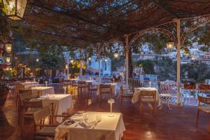 um restaurante com mesas brancas, cadeiras e luzes em Hotel Poseidon em Positano