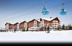 een skilodge in de sneeuw met een skilift bij Kempinski Hotel Grand Arena Bansko in Bansko