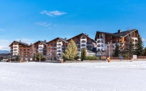 een groep gebouwen in de sneeuw naast een veld bij Kempinski Hotel Grand Arena Bansko in Bansko