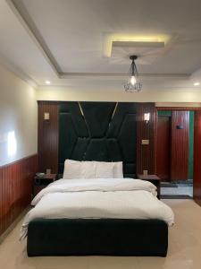 een slaapkamer met een groot bed met een groen hoofdeinde bij Mussiaree Hotel in Murree