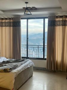 een slaapkamer met een bed en een groot raam bij Mussiaree Hotel in Murree