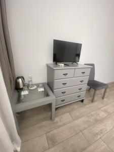 een kamer met een dressoir met een tv en een stoel bij Pallada Hotel in Ternopilʼ