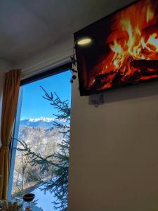 a television hanging on a wall next to a window at Touch the Sky in Moieciu de Jos