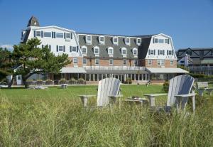 duas cadeiras brancas sentadas na relva em frente a um edifício em Newport Beach Hotel & Suites em Middletown