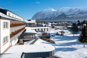 una ciudad cubierta de nieve con una montaña en el fondo en Hotel-Restaurant Grimmingblick, en Bad Mitterndorf