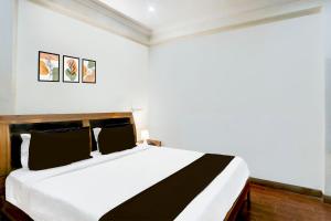 a bedroom with a large white bed with black pillows at Hotel O VG Grand in Madhapur