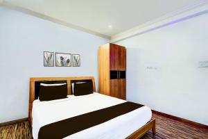 a bedroom with a bed with white sheets and black pillows at Hotel O VG Grand in Madhapur