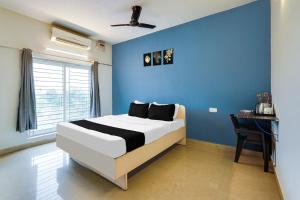 a bedroom with a blue wall and a bed and a desk at Hotel O ECR Stays Near Nemmeli Beach formerly GVS Homes in Chennai