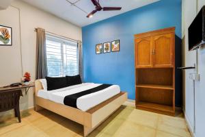 a bedroom with a bed and a blue wall at Hotel O ECR Stays Near Nemmeli Beach formerly GVS Homes in Chennai