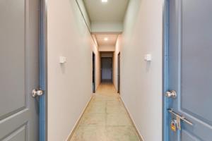 a corridor of an empty hallway with blue doors at Hotel O ECR Stays Near Nemmeli Beach formerly GVS Homes in Chennai