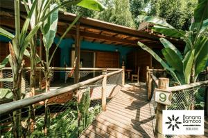 Banana Bamboo Ecolodge في أوباتوبا: ممشى خشبي يؤدي إلى منزل مع شرفة