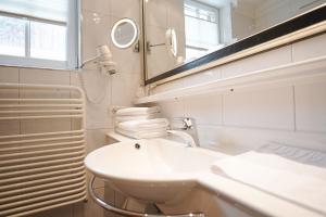 a white bathroom with a sink and a mirror at Hotel Acerina Superior in Lech am Arlberg