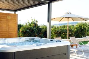 un jacuzzi en un patio con sombrilla en Frunze Luxury Apartments, en Nauplia