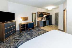 Candlewood Suites Fayetteville by IHG في فايتيفيل: غرفة فندقية بسرير ومكتب مع تلفزيون