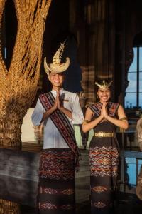 dos mujeres con ropa tradicional de pie frente a un árbol en The Apurva Kempinski Bali, en Nusa Dua