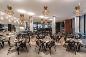 a dining room with tables and chairs and chandeliers at Hyatt Centric Candolim Goa in Calangute