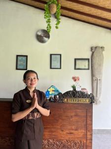 una mujer parada frente a una mesa con sus manos en WIRA Homestay & Spa, en Uluwatu