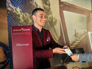 アル・ホセイマにあるMercure Quemado Al-Hoceima Resortの携帯電話を持つ看板の横に立つ男