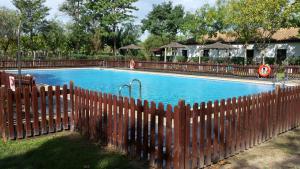 une clôture en bois en face d'une piscine dans l'établissement Camping La Aldea, à El Rocío