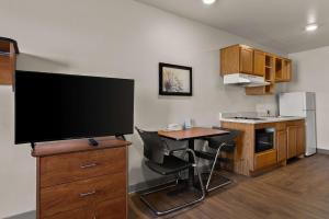 cocina pequeña con mesa y TV de pantalla grande en WoodSpring Suites Champaign near University, en Champaign