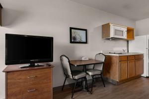 Habitación con mesa con 2 sillas y TV. en WoodSpring Suites Champaign near University, en Champaign