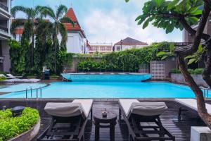 una piscina con tumbonas y un complejo en The Vira Bali Boutique Hotel & Suite, en Kuta