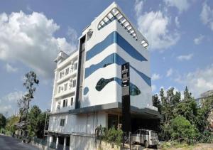 un edificio blu e bianco con un'auto parcheggiata di fronte di Aurora Hotels and Resorts a Pulickamaly