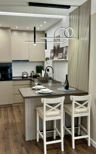 a kitchen with a island with two chairs and a table at Premium Line Apartman in Sombor