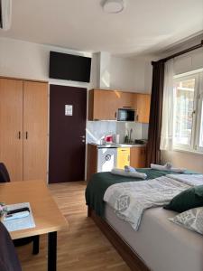 ein Schlafzimmer mit einem Bett und einem Tisch sowie eine Küche in der Unterkunft Apart AS in Mostar