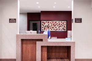 Candlewood Suites Fayetteville by IHG في فايتيفيل: امرأة تقف خلف كونتر في الحمام