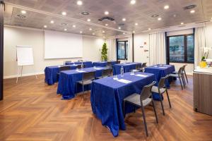 a conference room with blue tables and chairs and a whiteboard at Best Western Plus Borgolecco Hotel in Arcore