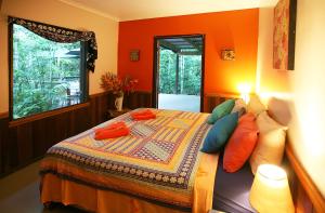 een slaapkamer met oranje muren en een bed met kussens bij Tropical Bliss bed and breakfast in Mena Creek