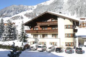 duży budynek z samochodami zaparkowanymi na śniegu w obiekcie Hotel Garni Senn w mieście Sankt Anton am Arlberg