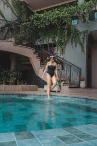 Eine Frau im Bikini steht neben einem Pool. in der Unterkunft Hotel Osvé Boutique Cali in Cali