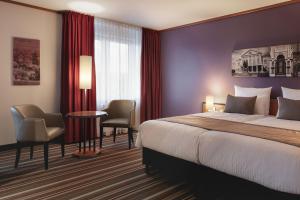 Habitación de hotel con cama, mesa y sillas en Leonardo Hotel Weimar, en Weimar