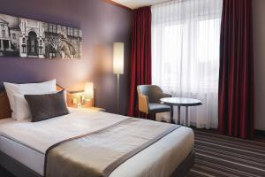 Habitación de hotel con cama, silla y mesa en Leonardo Hotel Weimar, en Weimar