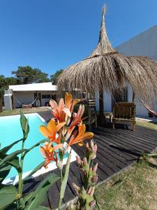 a deck with a hut and a swimming pool at Solar de la Viuda in Punta Del Diablo