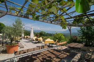 un patio con tavoli, sedie e ombrellone bianco di Hotel Römerrast a Caldaro