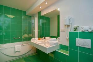 a green bathroom with a sink and a mirror at Hotel Rotondo in Trogir