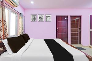 una camera da letto con un grande letto e pareti rosa di Super Hotel O Daba Gardens Near Dolphin Junction a Alipur